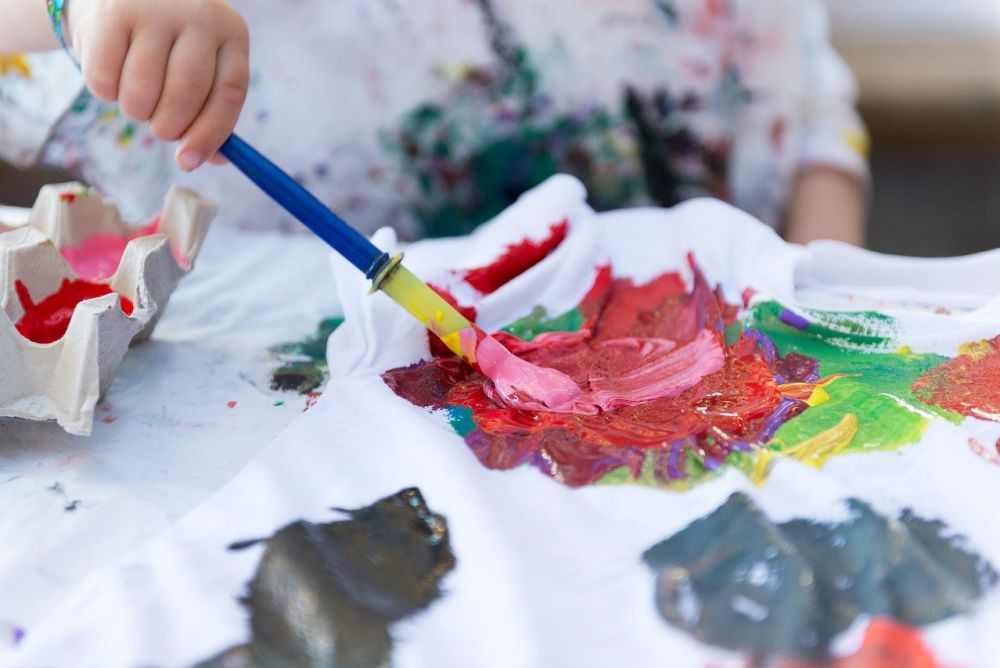 Kinderhand hält Pinsel in Acrylfarbe