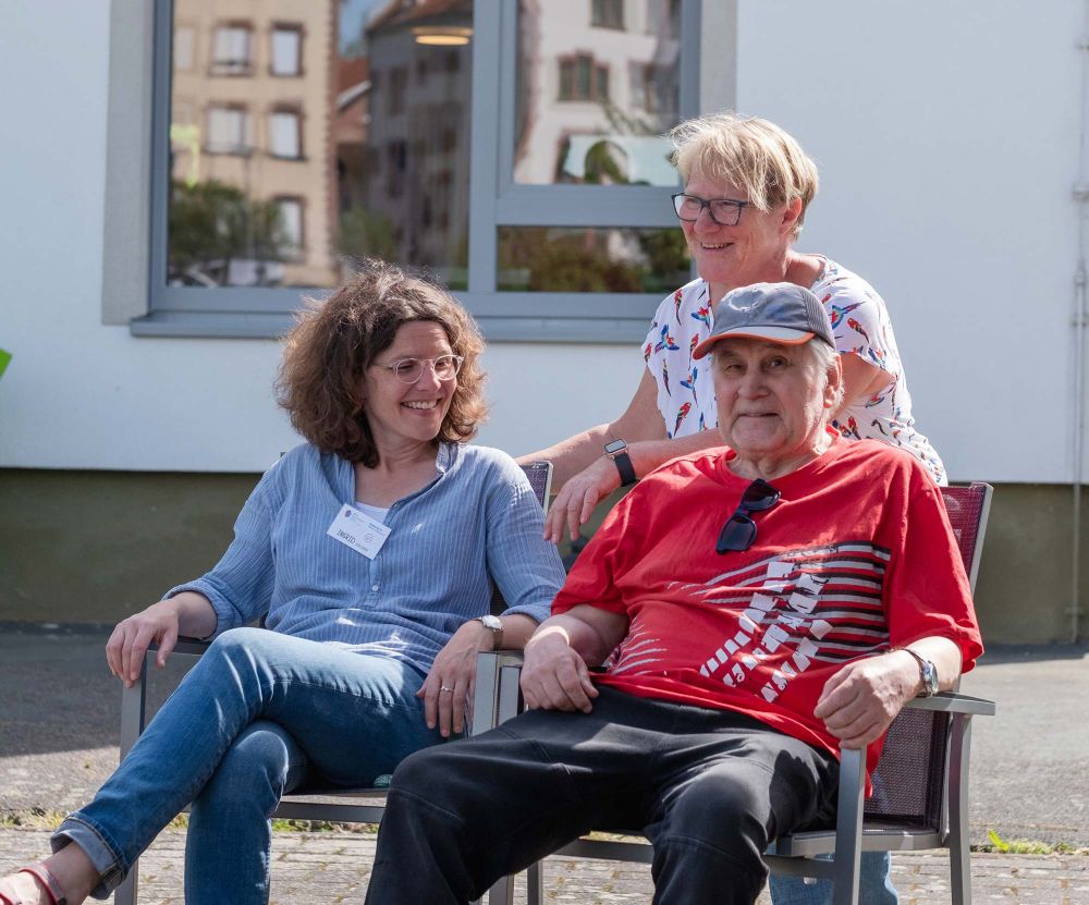 Zwei Frauen und ein Mann auf Stühlen draußen